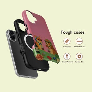 May include: A layered phone case with a pink exterior, black interior, and a silver phone. The pink case features a colourful illustration of two dogs wearing sunglasses and headscarves, playing poker. The text "Tough cases" is also visible.