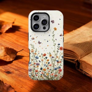 May include: A phone case with a floral design. The case is white with a colorful watercolor illustration of wildflowers and butterflies. The flowers are in shades of red, orange, yellow, blue, and purple. The case has a camera cutout and buttons.