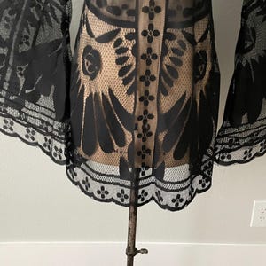A close-up of the hem on the sheer black bohemian Bell sleeve mini dress