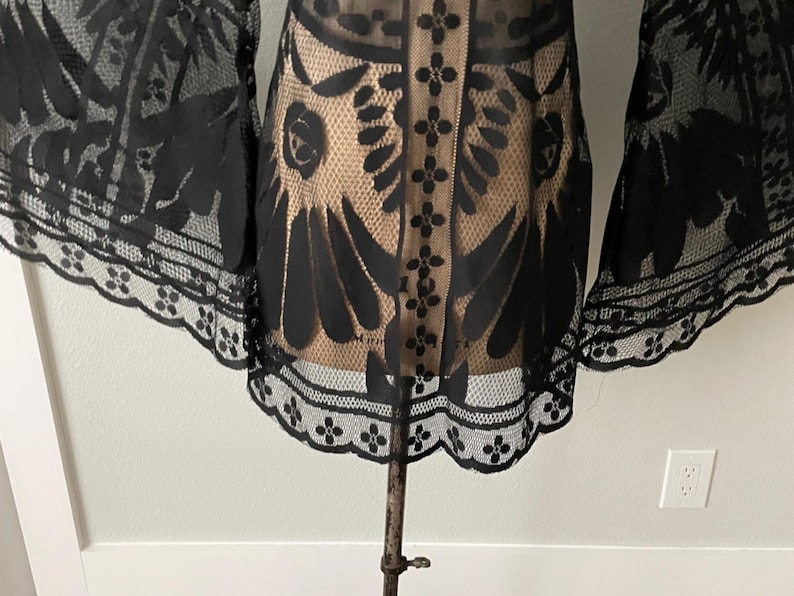 A close-up of the hem on the sheer black bohemian Bell sleeve mini dress