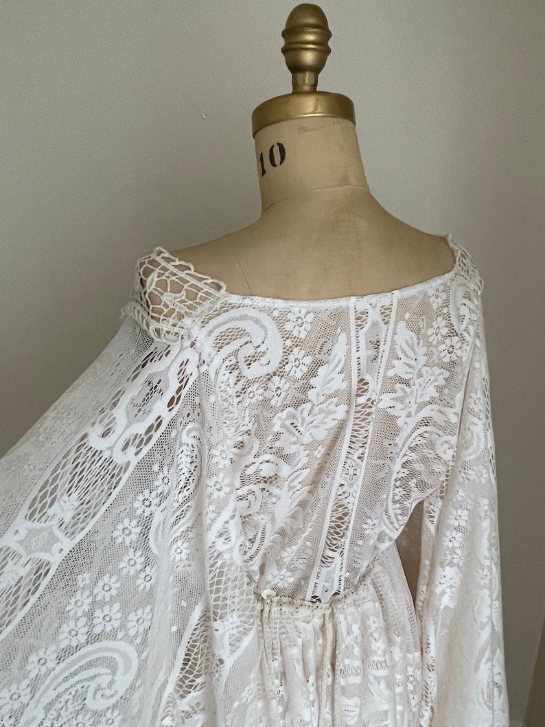 back view of a off-white ivory lace wedding dress on Etsy that features long Bell sleeves in an adjustable waist