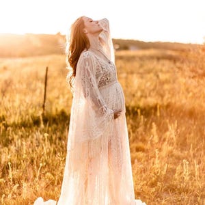 actual pregnant bride, wearing a long ivory lace, Bohemian wedding gown with long bell sleeves that have fringe and an extra long maxi skirt