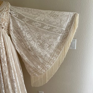 close-up photo of a long bell sleeve with fringe, which is part of a Bohemian lace wedding gown on Etsy