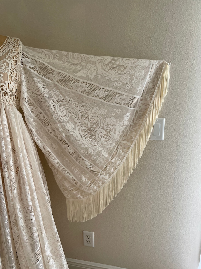 close-up photo of a long bell sleeve with fringe, which is part of a Bohemian lace wedding gown on Etsy