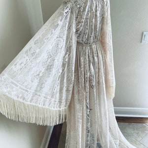 back view of a Bohemian lace wedding dress that is showing a close-up of the Bell sleeve shape with fringe and the drawstring waist