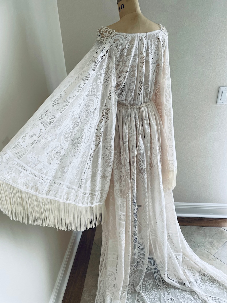 back view of a Bohemian lace wedding dress that is showing a close-up of the Bell sleeve shape with fringe and the drawstring waist