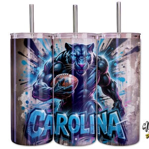 May include: Three stainless steel tumblers with a wraparound design. The design features a muscular black panther holding a football, with the word "CAROLINA" in blue graffiti-style lettering. The background has a distressed, urban art aesthetic.
