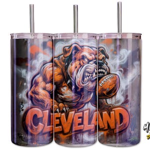 May include: Three stainless steel tumblers with lids and straws. Each tumbler has a muscular bulldog graphic holding a football, with the word "Cleveland" in orange. The background has a graffiti-style design.