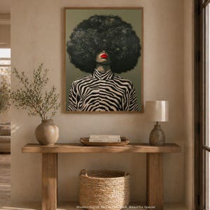 May include: A framed art print featuring a stylized portrait of a person with a large, curly afro. The person wears a black and white zebra-striped shirt and has bright red lipstick. The artwork is displayed above a wooden console table.