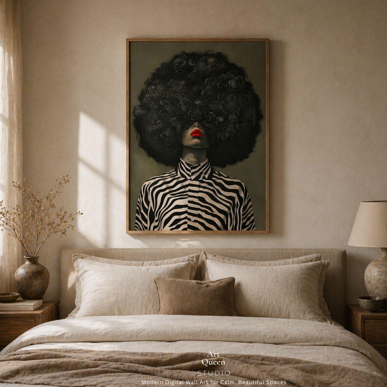 May include: A framed art print featuring a woman with a large, textured black afro and red lipstick. She wears a black and white zebra-striped shirt. The artwork is displayed above a bed with neutral-toned bedding. The text "Art Queen Studio" is visible.