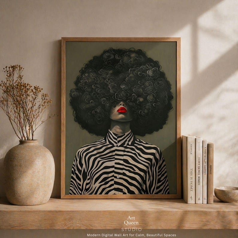May include: Framed digital wall art featuring a person with a large, dark, curly afro. The person wears a black and white zebra-striped shirt and has bright red lipstick. The art is displayed on a wooden shelf with books and a vase. The text "Art Queen Studio" is visible.
