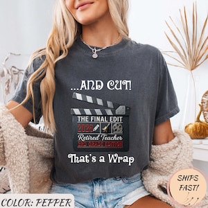 Peut inclure: T-shirt de couleur poivre avec le texte "...AND CUT!" au-dessus d'un graphisme de clap de cinéma. Le clap de cinéma indique "THE FINAL EDIT 2026 Retired Teacher 3RD GRADE EDITION That's a Wrap."