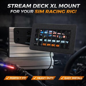 May include: A black Stream Deck XL mount for a sim racing rig. The mount has a black control panel with illuminated buttons showing graphics. The text "THE BARBARIAN GARAGE" is visible. It's attached to a silver metal frame.