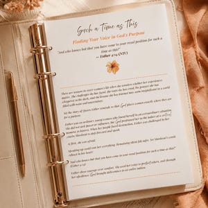Peut inclure: Un classeur à anneaux de couleur crème contenant une page imprimée intitulée Such a Time as This, Finding Your Voice in God's Purpose, avec le texte d'Esther 4:14, une petite illustration de fleur orange et un stylo doré dans le classeur.