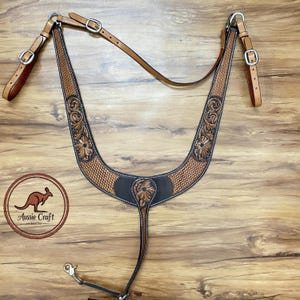 Puede incluir: Un petral de caballo de cuero hecho a mano con herramientas florales y un patrón de tejido de cesta. El petral es marrón y negro con herrajes plateados. La imagen también incluye el logotipo de Aussie Craft Leather.