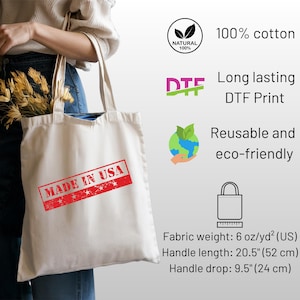 Puede incluir: Bolso tote color crema con el texto "MADE IN USA" en un sello rojo. Hecho de 100% algod&oacute;n, con impresi&oacute;n DTF. Longitud del asa: 52 cm, ca&iacute;da del asa: 24 cm. Reutilizable y ecol&oacute;gico.