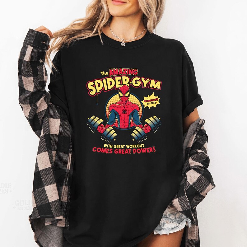 Może przedstawiać: Czarna koszulka z grafiką Spider-Mana. Projekt zawiera tekst "The Amazing Spider-Gym" i "With Great Workout Comes Great Power!" w kolorze czerwonym i ż&oacute;łtym. Grafika przedstawia Spider-Mana podnoszącego ciężary.