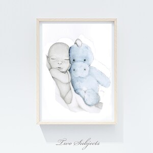 May include: Watercolor print of a sleeping baby and a blue stuffed hippo. The baby is in grayscale, and the hippo is light blue. The print is framed in a light wood frame. The text "Two Subjects" is at the bottom.