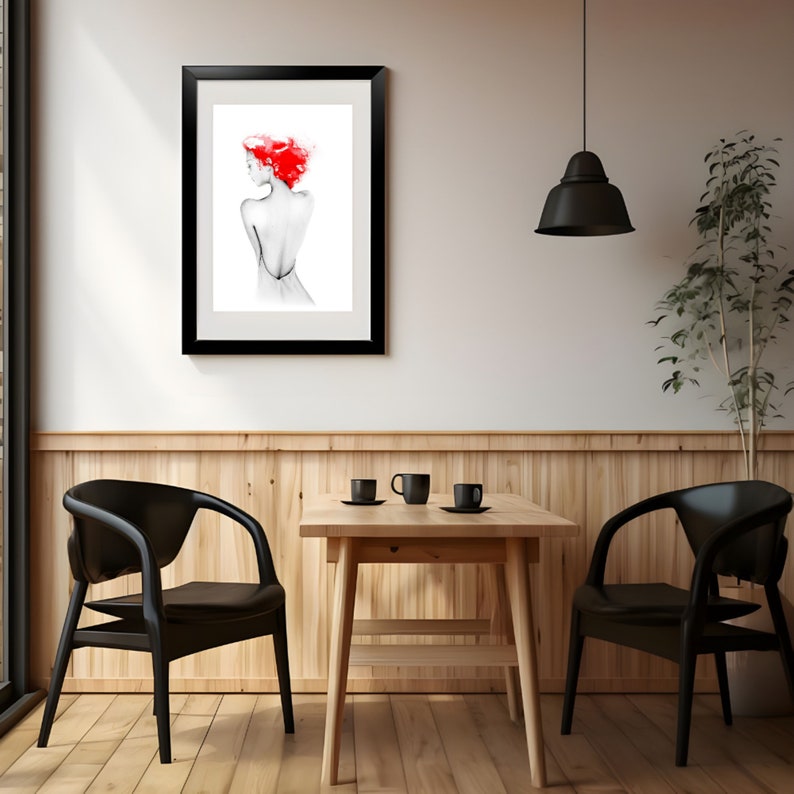 May include: A black framed print of a woman with red hair, hanging on a white wall above a wooden table with two black chairs. The table has three cups and saucers on it.