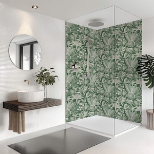 May include: A contemporary bathroom featuring a white sink, a circular mirror, and a shower enclosure with a green floral wallpaper. A dark grey rug rests on the white tiled floor. A potted plant is in the corner.