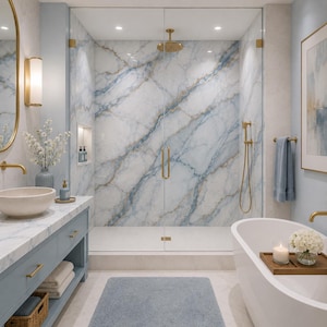 May include: A luxurious bathroom with a marble shower and vanity. The shower features a white and blue marble design with gold fixtures. A white bathtub with a wooden tray, candle, and flowers is in the foreground. The vanity is light blue with a marble countertop.