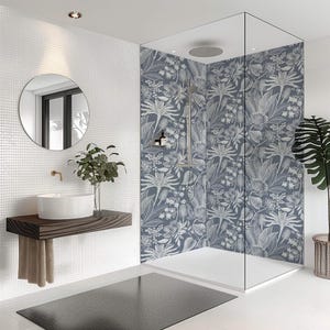 Può includere: Bagno moderno con doccia con pareti in vetro con stampa botanica blu e bianca. La stanza comprende un lavabo bianco su una mensola in legno, uno specchio rotondo e una pianta in vaso, creando un'atmosfera da spa.