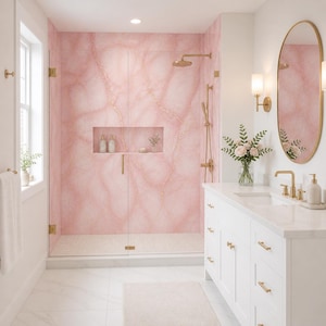 May include: A luxurious bathroom with a pink marble shower and gold fixtures. The shower features a built-in niche for toiletries. A white vanity with gold hardware and an oval mirror complete the elegant design. A vase of flowers adds a touch of freshness.