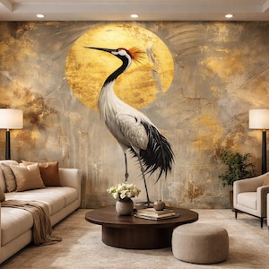 Könnte beinhalten: Ein Wohnzimmer mit einem großen Wandgemälde eines Kranichs vor einer goldenen Sonne. Der Kranich ist hauptsächlich weiß und schwarz mit einem roten Kamm. Der Raum umfasst ein beiges Sofa, Sessel, einen Couchtisch und Lampen, was eine ruhige und künstlerische Atmosphäre schafft.