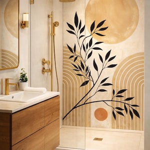 May include: A modern bathroom with a wooden vanity, gold fixtures, and a glass shower. The shower wall features a mural with beige circles, arches, and a black branch design. A small plant sits on the vanity.