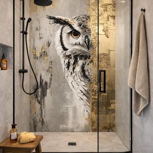 May include: A contemporary shower cubicle featuring an owl mural. The artwork depicts a detailed owl with brown eyes, set against a backdrop of grey and gold textures. The shower has black fixtures and a wooden stool.