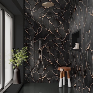May include: A modern bathroom with black tile walls featuring a gold vein design. The shower includes a rain shower head and handheld shower. A wooden stool with white-tipped legs sits near the shower. A vase with greenery sits by the window.