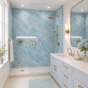 May include: A modern bathroom with a blue marble-patterned shower wall and a light blue vanity. The shower features gold-colored fixtures, including a showerhead and handheld sprayer. A gold-framed mirror and a vase of blue flowers add elegance.