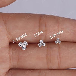 May include: Three small, silver-colored stud earrings with a cluster of three clear gemstones. The earrings are displayed in three sizes: 2.50 mm, 2 mm, and 1.50 mm. The earrings are on a light background.