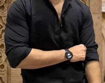 May include: Black long-sleeved shirt with a mandarin collar and buttoned placket. A black smartwatch with a round face and black strap is visible on the wrist. The shirt has a textured appearance.