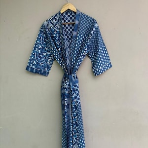 May include: A blue and white patterned robe with a tie closure, hanging on a wooden hanger. The robe features various patterns, including floral and geometric designs, in shades of blue and white.