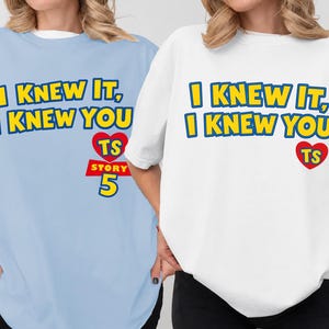 May include: A light blue t-shirt and a white t-shirt, each featuring the yellow text I KNEW IT, I KNEW YOU with a red heart containing the letters TS above the red text STORY 5 in a bold, blocky font style on the front of the garments.