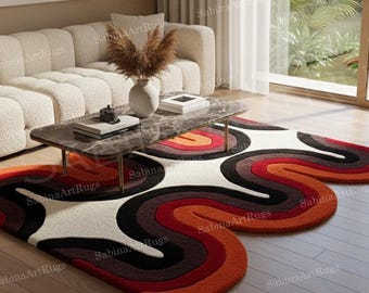 Puede incluir: Salón moderno con sofá crema, mesa de centro de mármol y dos alfombras abstractas. Las alfombras tienen un diseño ondulado en tonos naranja, rojo, marrón y negro. La habitación tiene grandes ventanales y suelo de madera.
