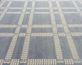 May include: A large, rectangular rug with a light blue background and a repeating grid pattern. The grid is formed by wide, off-white bands with a stylized leaf design. The rug has a soft, textured appearance.