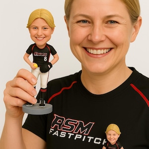 Könnte beinhalten: Wackelkopf-Figur einer Softballspielerin in schwarzer und roter Uniform mit der Nummer 8. Die Figur hält einen gelben Softball und trägt einen schwarzen Handschuh. Auf dem T-Shirt steht "RSM FASTPITCH".
