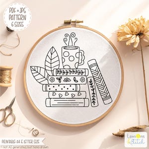 May include: A black and white embroidery hoop featuring a stack of books, a steaming mug, and leaves. The design includes the text "PDF + JPG PATTERN 6 SIZES" and "PRINTABLE: A4 & LETTER SIZE". The embroidery is set in a wooden hoop.