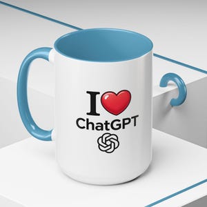 May include: White ceramic mug with a blue interior and handle. The mug features the text "I ❤️ ChatGPT" in black and red, along with the ChatGPT logo. The mug is on a white surface.