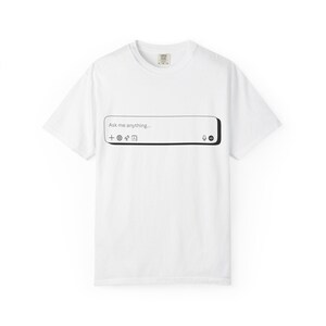 May include: White t-shirt with a black and white graphic of a chat box that says "Ask me anything...". The chat box includes icons for adding content, a globe, a star, and a microphone.