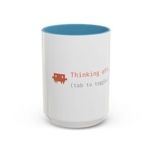 May include: White ceramic mug with a blue interior. The mug features the text "Thinking off..." and a pixelated brown graphic. Below the text is "(tab to toggle)".
