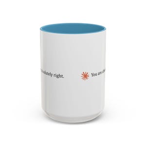 May include: A white ceramic mug with a bright blue interior. The exterior features the text 'You are absolutely right.' printed in black, accompanied by a small, orange, star-shaped graphic icon positioned between the words.