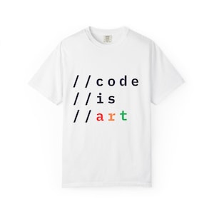 May include: White t-shirt with the text "//code //is //art" in black, red, orange, and green. The shirt has a crew neck and short sleeves. The design is centered on the front of the shirt.