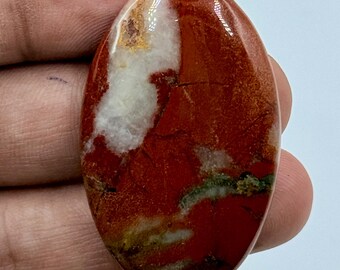 以下が含まれることがあります： 深い赤茶色のベースカラーに、白く半透明な石英のようなインクルージョンと、滑らかで光沢のある表面全体に広がる濃い緑色の鉱物の脈が見られる、楕円形の磨かれた宝石のルース（カボション）。