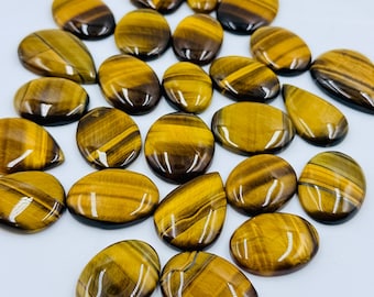 Puede incluir: Una colección de piedras preciosas de ojo de tigre pulidas en varias formas, incluyendo óvalos y gotas. Cada piedra presenta una superficie lisa y brillante con bandas chatoyantes de color marrón dorado y oscuro características.