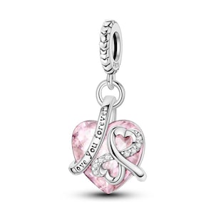 May include: A silver charm featuring a pink heart-shaped crystal and a ribbon design. The ribbon is embellished with small, clear crystals and the words "love you forever". The charm has a loop for attaching to a bracelet or necklace.