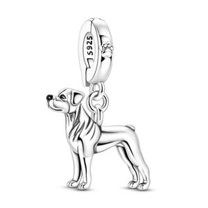 May include: A silver dog charm with a detailed design. The charm is attached to a loop with a paw print and the inscription "S925". The dog is depicted in a standing pose, with a polished finish and realistic features.