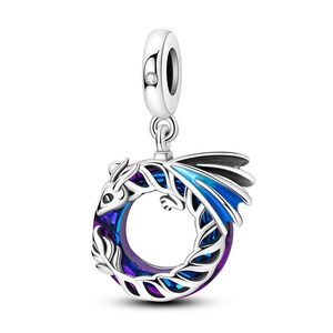 May include: A silver dragon charm with blue and purple detailing, forming a circular shape. The charm has a small clear gem on the top loop. Designed for use as a pendant or bracelet charm, it is a fantasy-themed accessory.